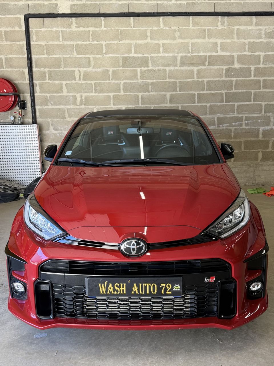 Toyota GR Yaris rouge de face après lavage, dans un garage